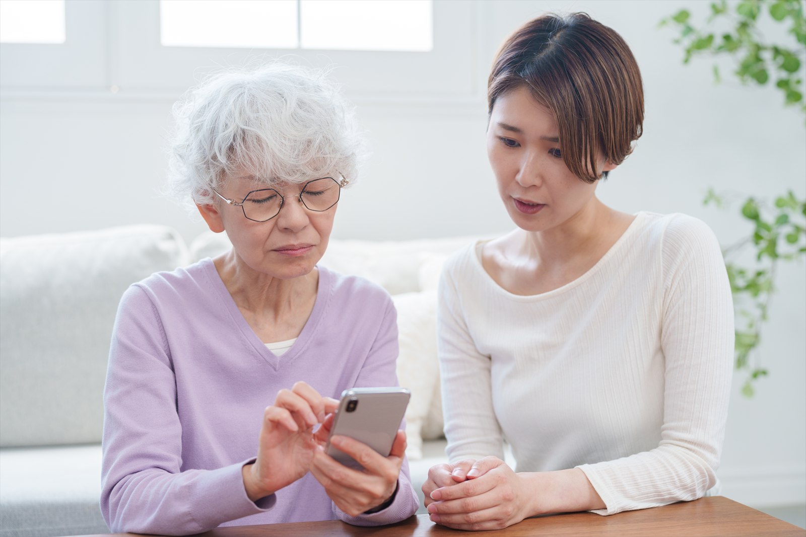 女性が高齢の女性にスマートフォンの使い方を案内している様子